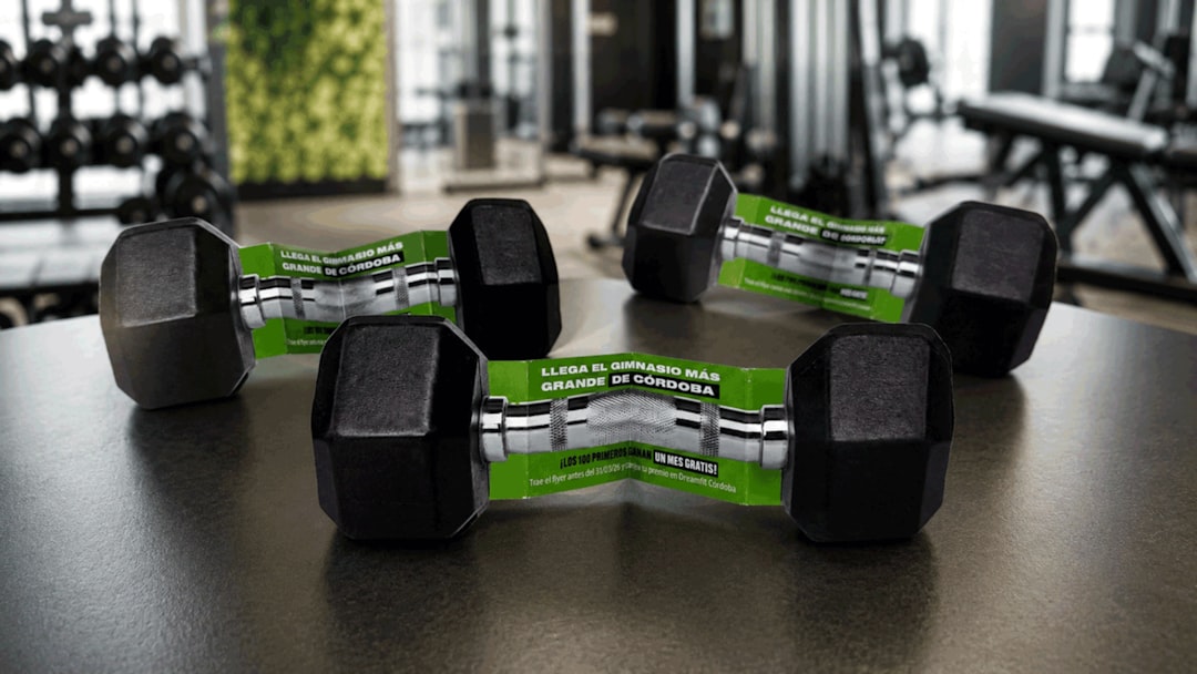 Two black dumbbells with green promotional paper bands on a dark table