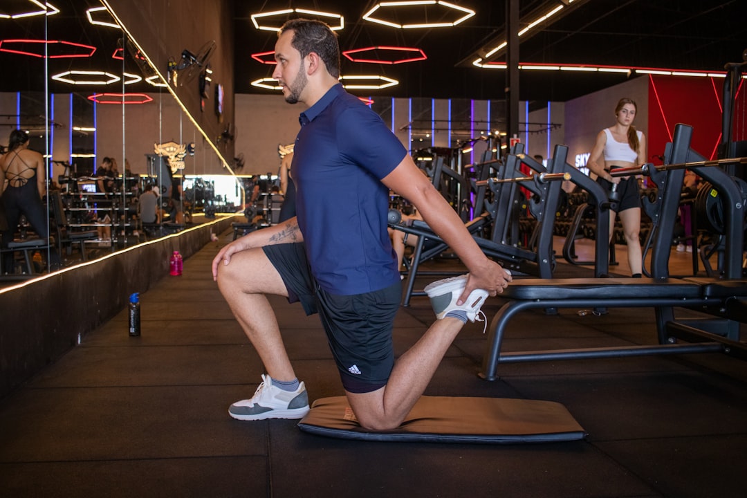Man stretching quadriceps on a mat in gym